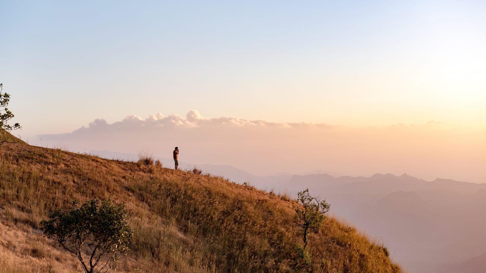 A distant walker on a broad grassy ridge in evening light