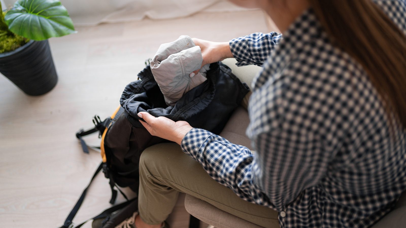 A walker packing a stuff sack into a black rucksack indoors before a trip